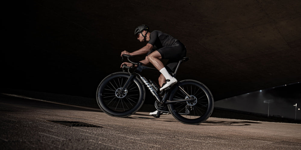 Racer riding a lightweight Mpc series carbon road bike under a concrete arch